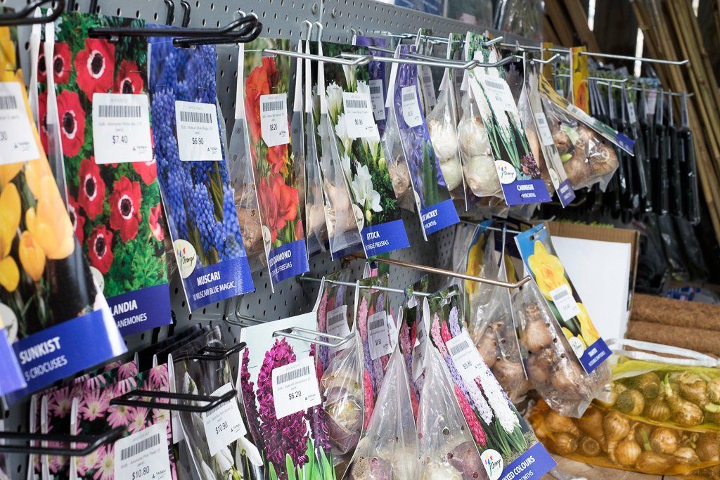 A display rack filled with various packets of flower bulbs and seeds, hanging for sale in a store.