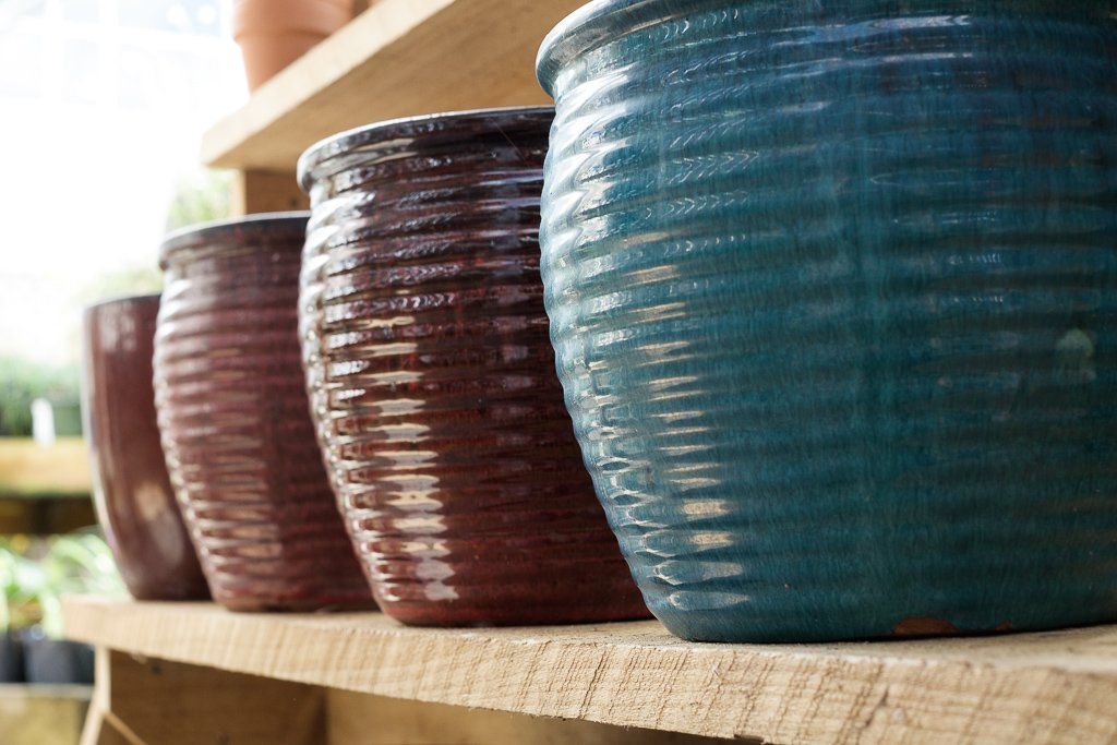 A row of blue and reddish-brown ribbed ceramic pots sitting on wooden shelves.