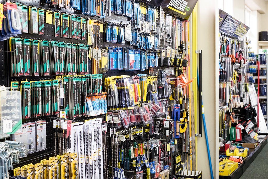 A well-stocked hardware store aisle displaying numerous tools hanging on pegboards and shelves.