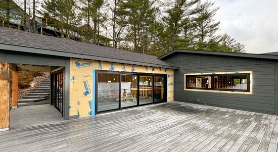 Exterior view of a building under construction, featuring glass doors and windows, and a partially finished roof.