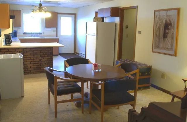 Cozy dining room and kitchen with round table, blue chairs, brick island, and a refrigerator nearby