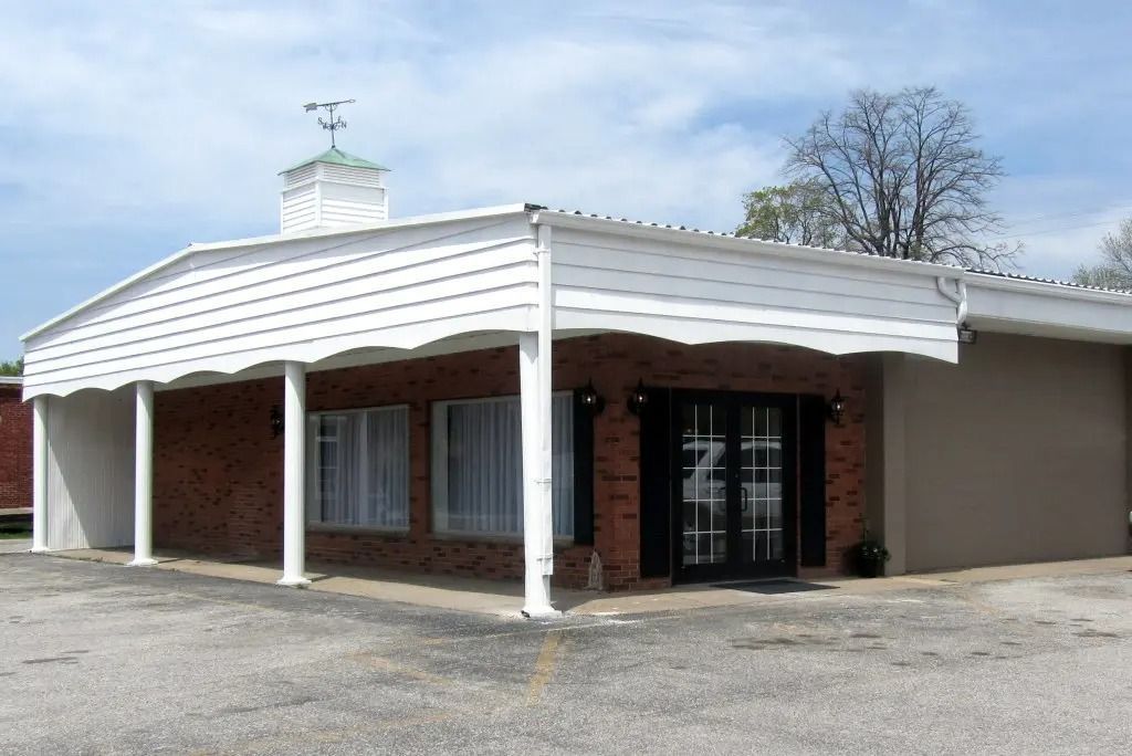 Single-story brick building with white roof trim and columns, viewed from the parking lot.