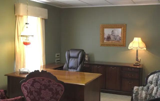 Quiet office with desk, leather chair, lamp, and framed wall art in muted green tones