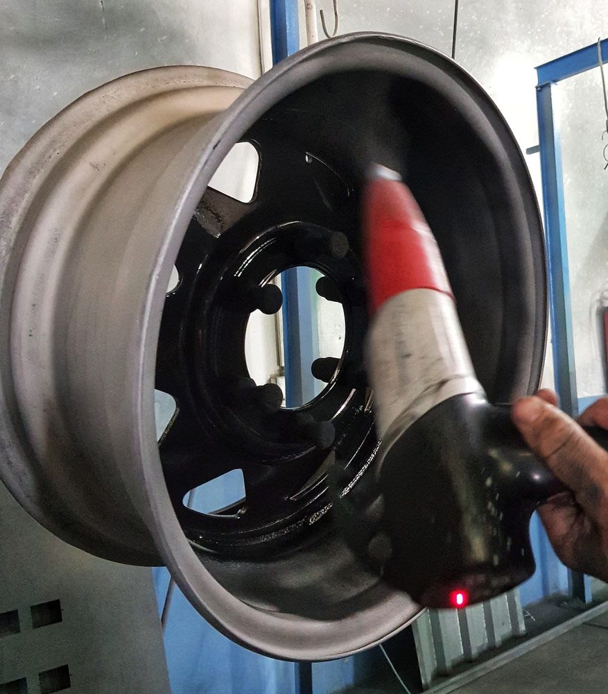 A Person is Holding a Red and White Cone in Front of a Wheel — Hastings Valley Powdercoaters in Taree, NSW