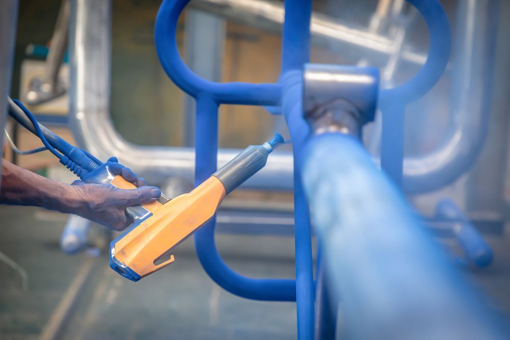 A Person is Spraying Blue Powder to a Metal — Hastings Valley Powdercoaters in South West Rocks, NSW