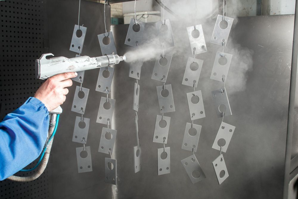 A Person is Spraying Powder Paint on a Piece of Metal — Hastings Valley Powdercoaters in Taree, NSW