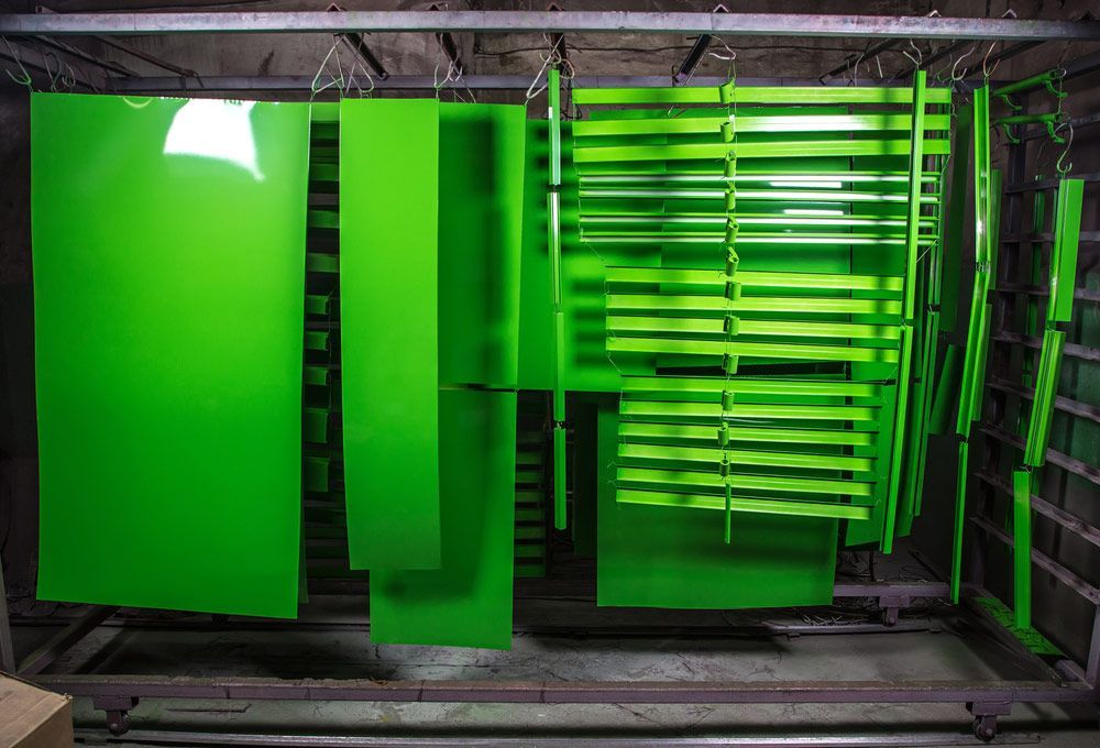 A Bunch of Green Pieces of Metal Are Hanging on a Rack — Hastings Valley Powdercoaters in Taree, NSW