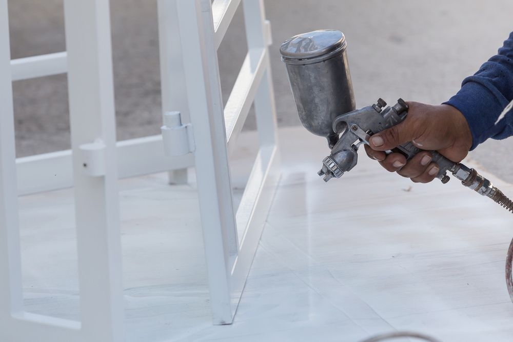 A Person is Spraying Powder on a Window Frame — Hastings Valley Powdercoaters in Taree, NSW