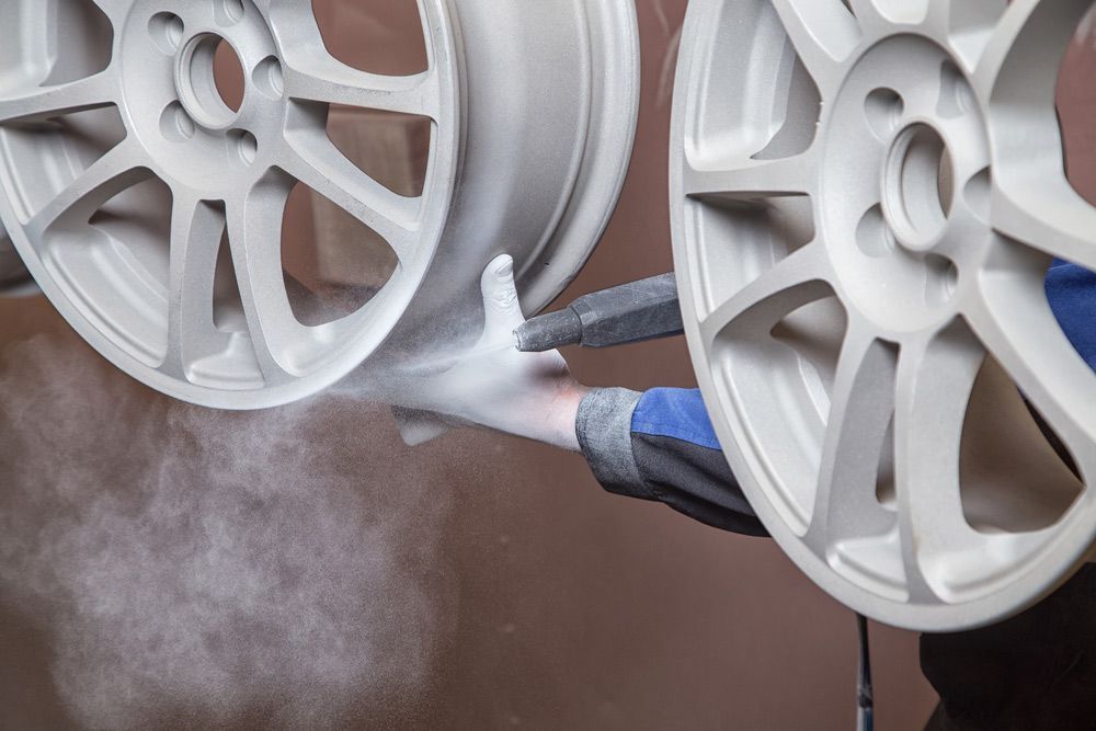 A Person is Coating a Pair of White Wheels — Hastings Valley Powdercoaters in Harrington, NSW
