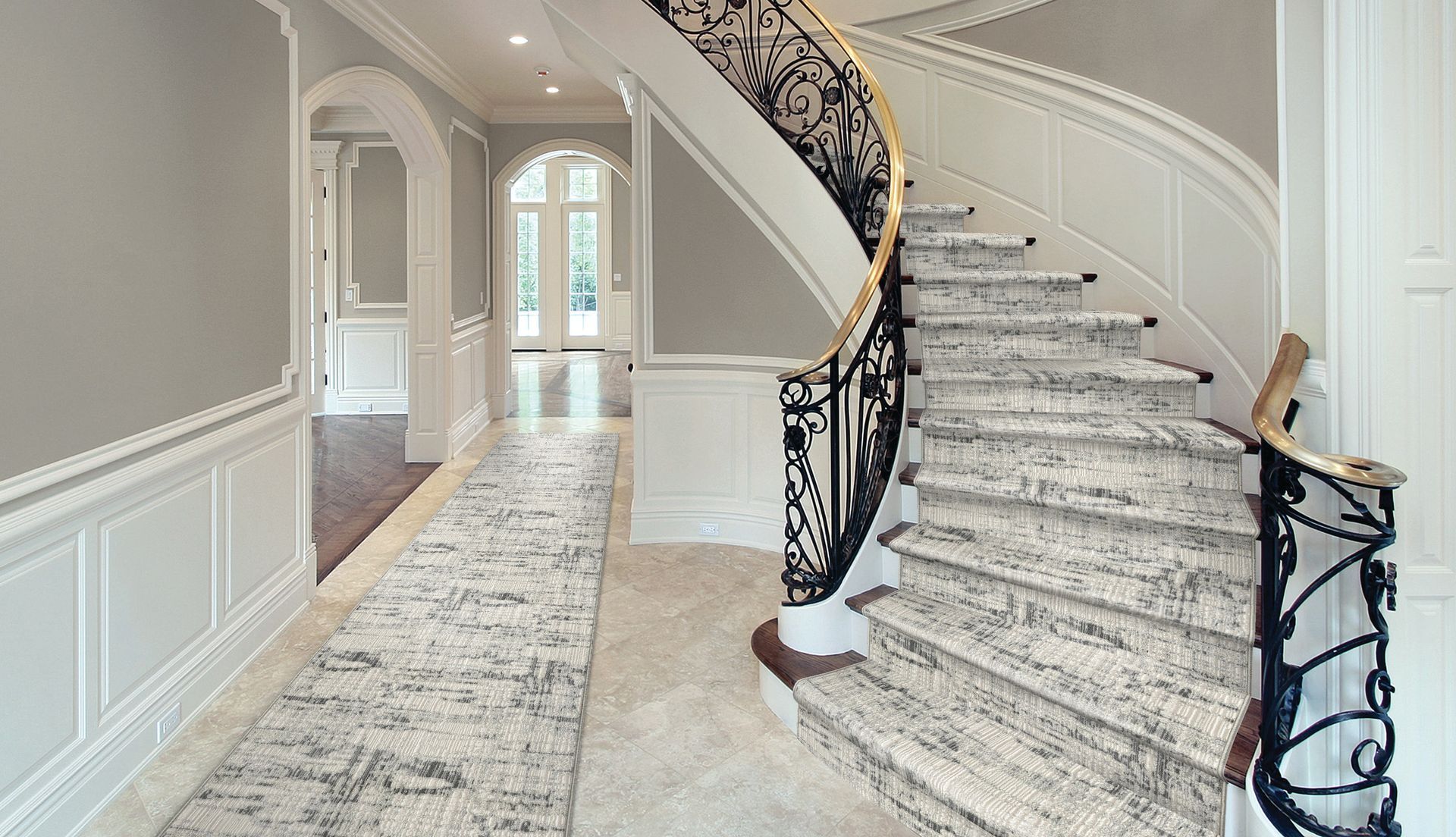 Elegant foyer with a curving staircase, marble steps, and a long hallway with arched doorway.