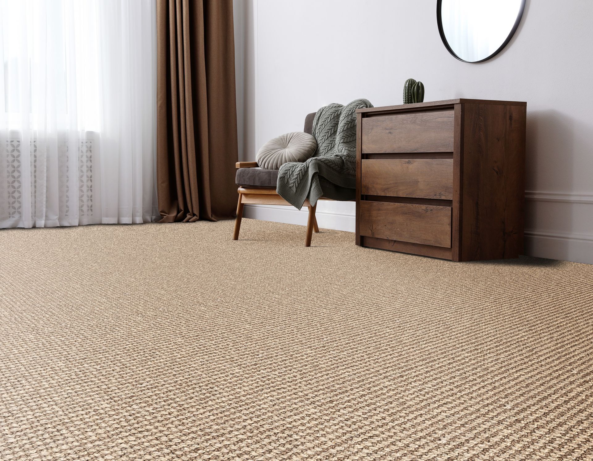 Room with woven beige rug, wooden dresser, chair, and window with curtains.