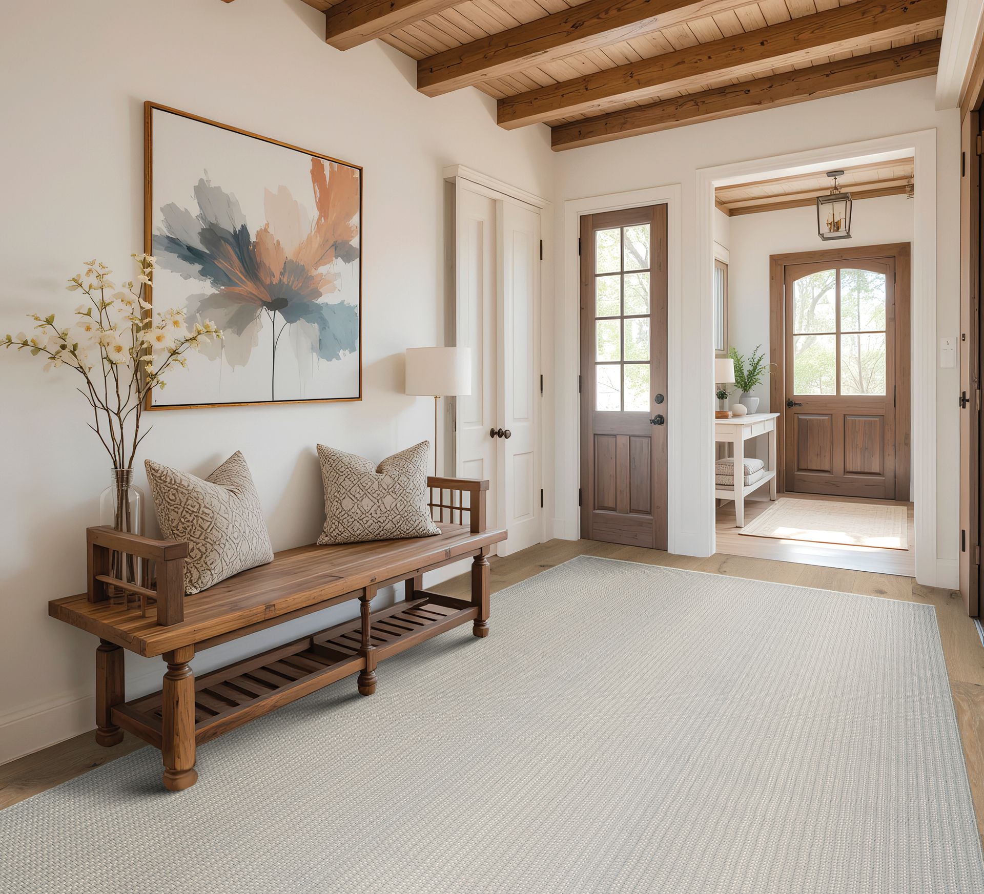 Hallway with wooden bench, art, and patterned rug; light and airy.