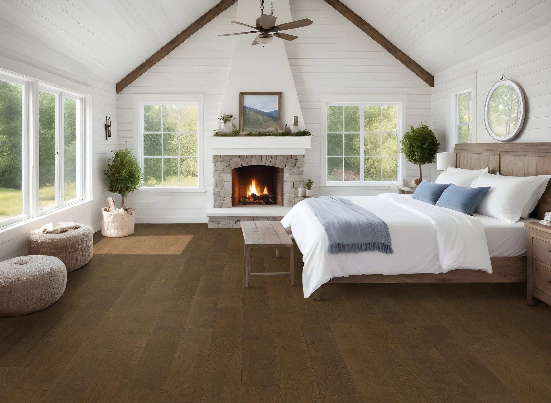 Bedroom with white walls, fireplace, windows, and wood flooring; a bed and seating.