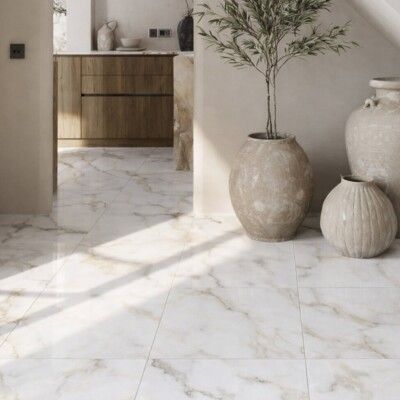 Marble tiled floor in a room, warm light with decorative pots, and a glimpse of a wooden kitchen.