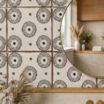 Bathroom wall with repeating black and white circular pattern tiles, round gold mirror.