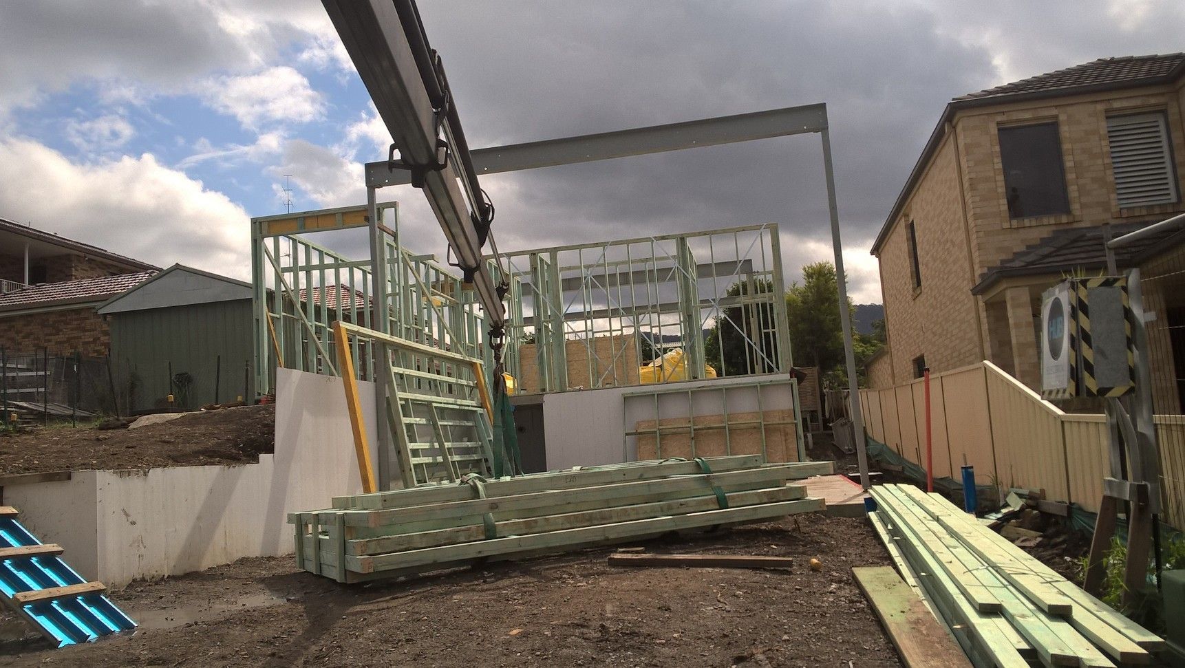 Timber wall frames crane-delivered to a residential construction site in West Wollongong, ready for installation.