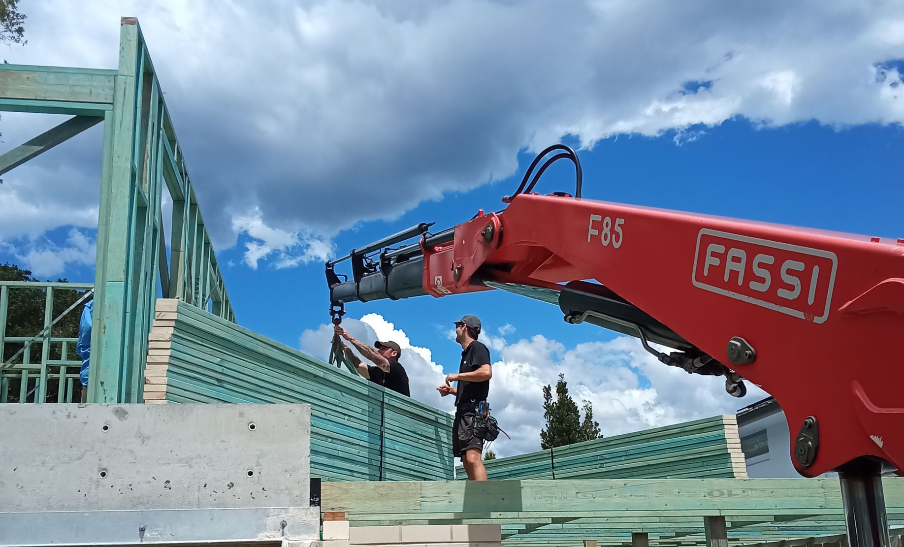 Roof trusses being delivered via crane truck showing wall frames