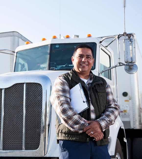 Smiling person standing in front of a white semi-truck outdoors