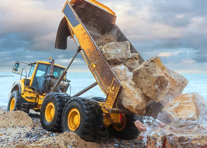 Yellow dump truck unloading rocks at a construction site