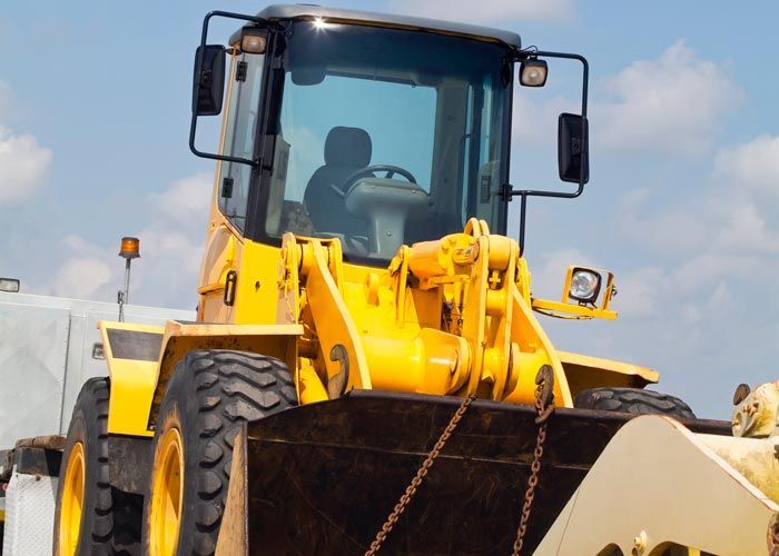 Yellow front loader construction vehicle with raised bucket under a blue sky