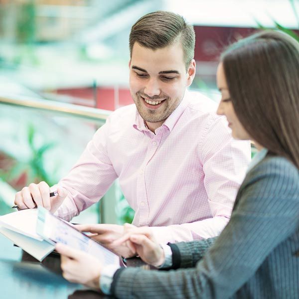 A man and woman reviewing documents and smiling at a table in a bright office lobby