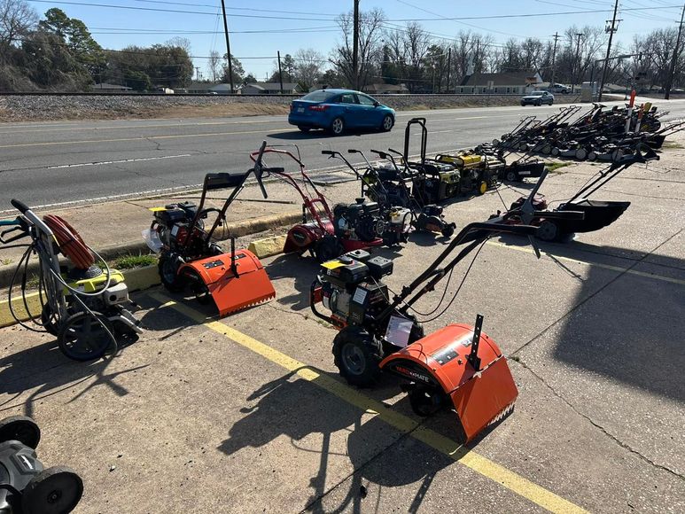 A row of snow blowers are parked in a parking lot.