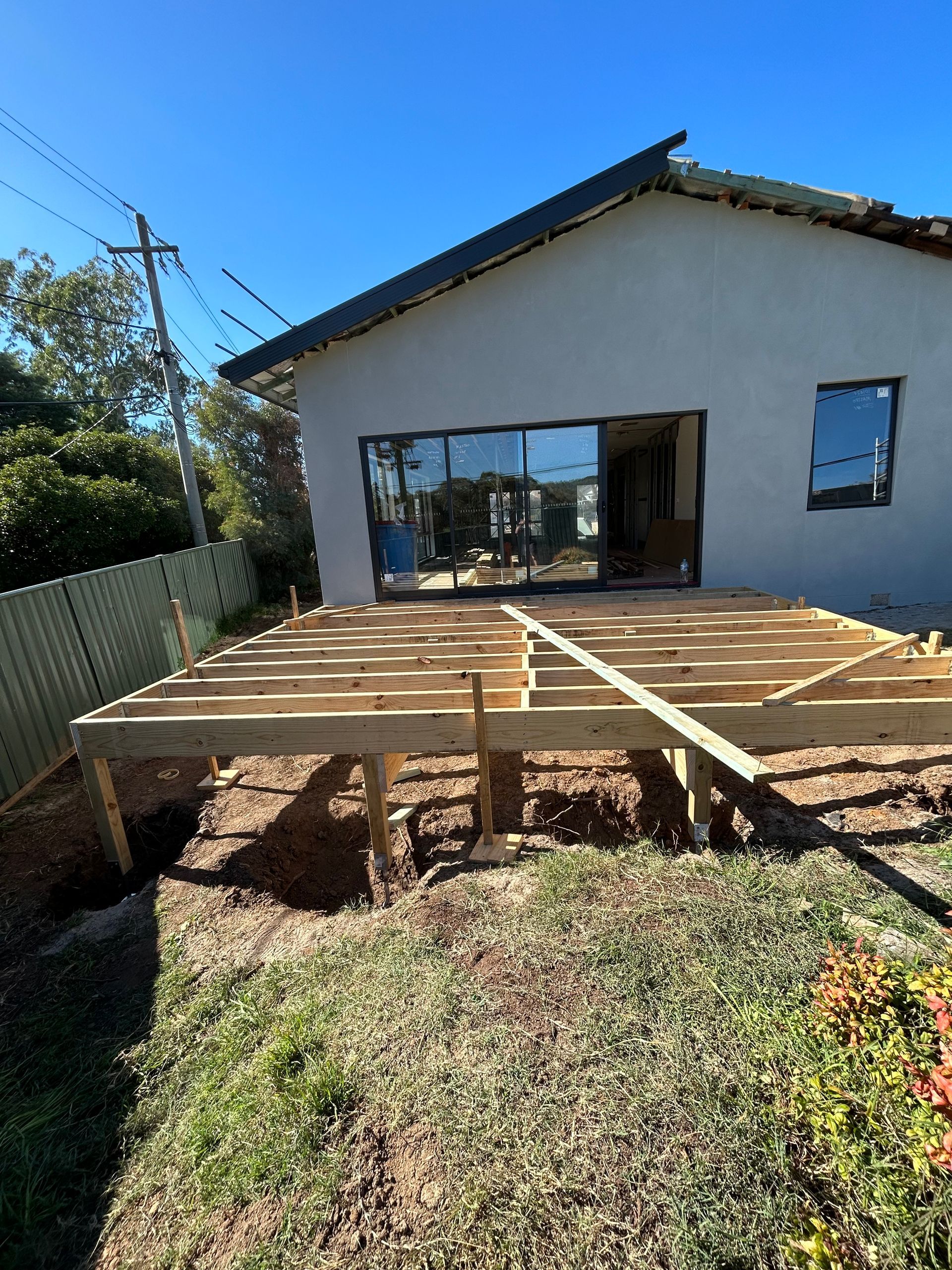 Construction of a wooden deck outside a house with sliding glass doors.