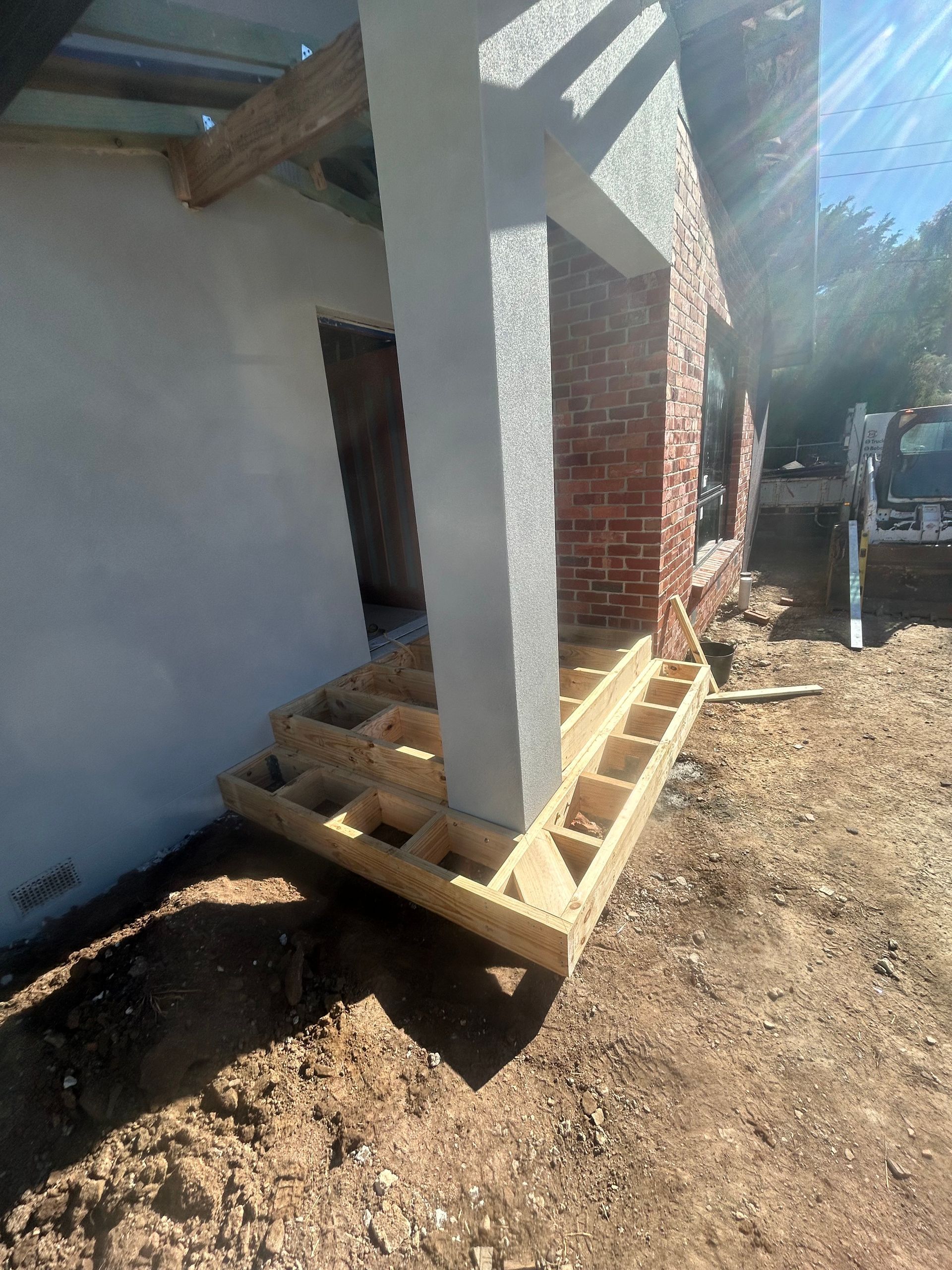 Wooden porch under construction; pillar and brickwork visible.