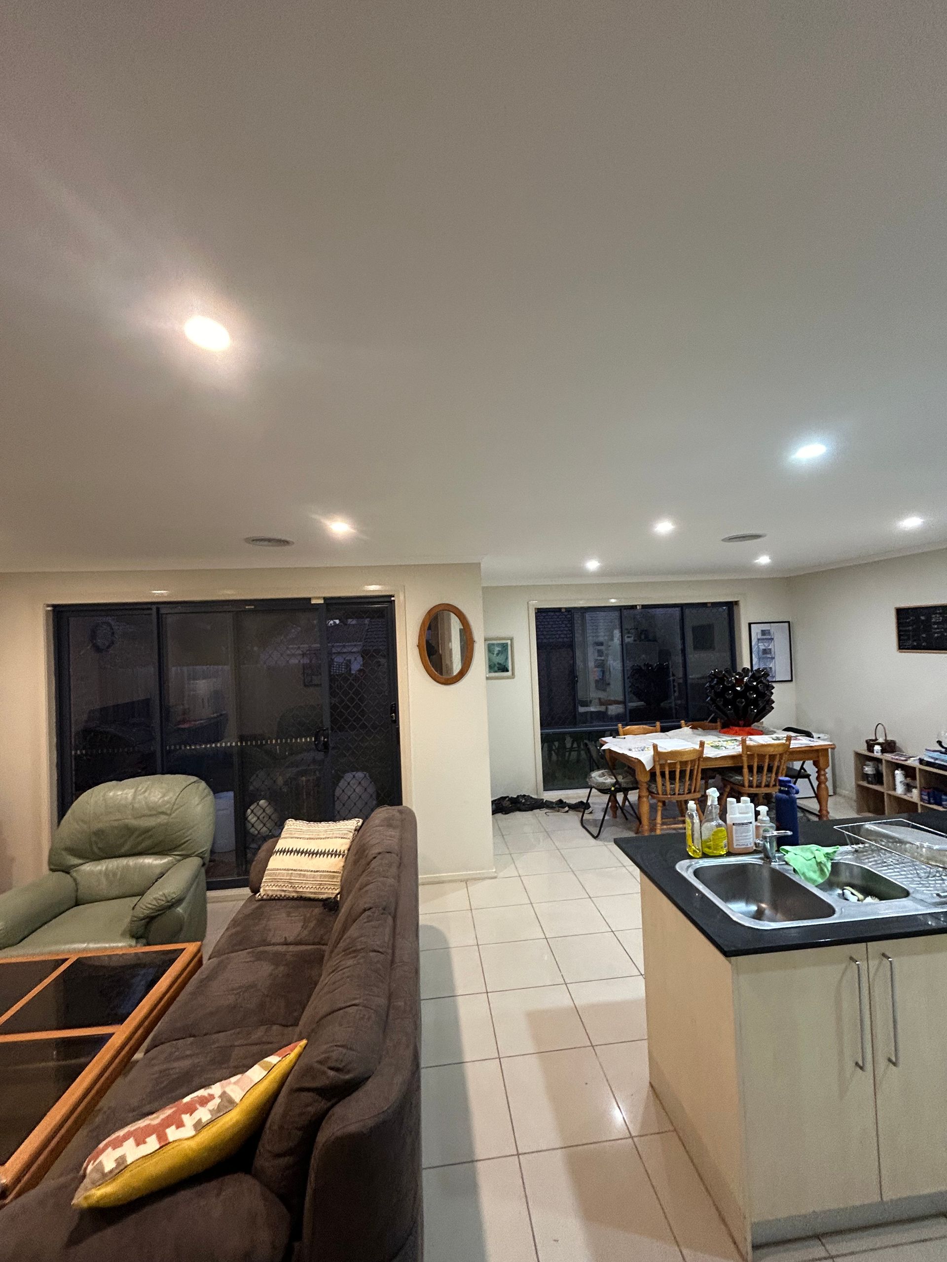 Living room with a brown couch, green armchair, and kitchen area.