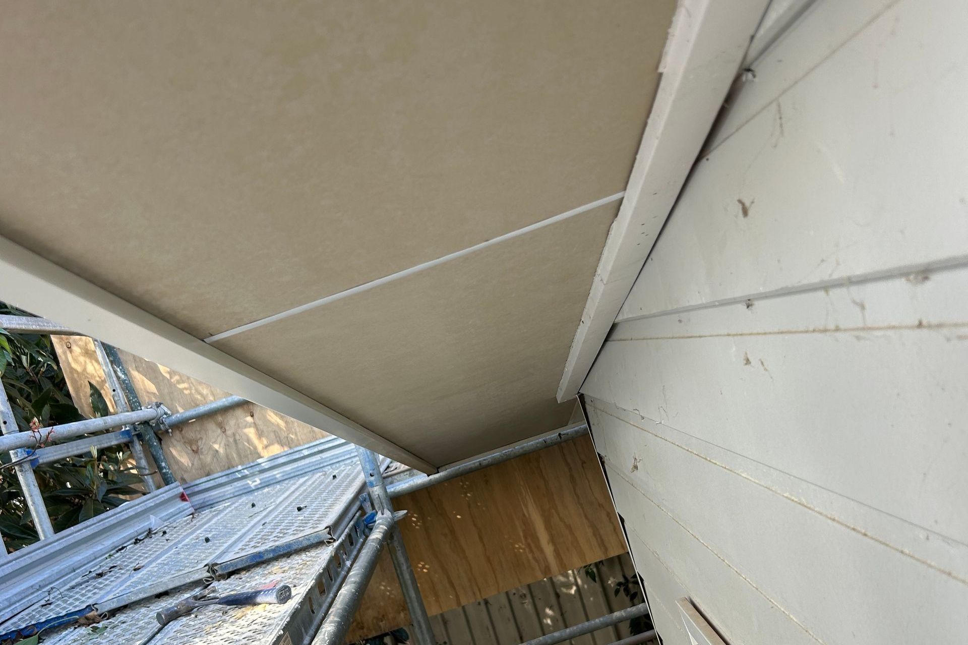Beige awning attached to a white wall, viewed from below.