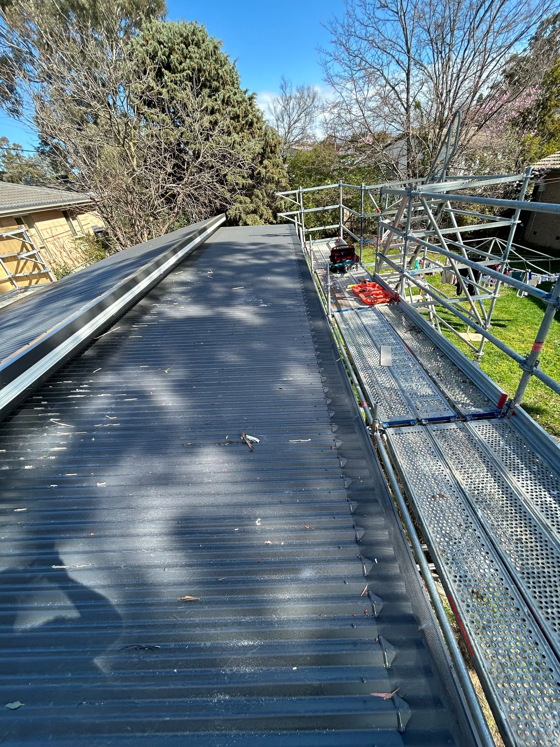 Black corrugated roof with scaffolding along the side, sunny day.