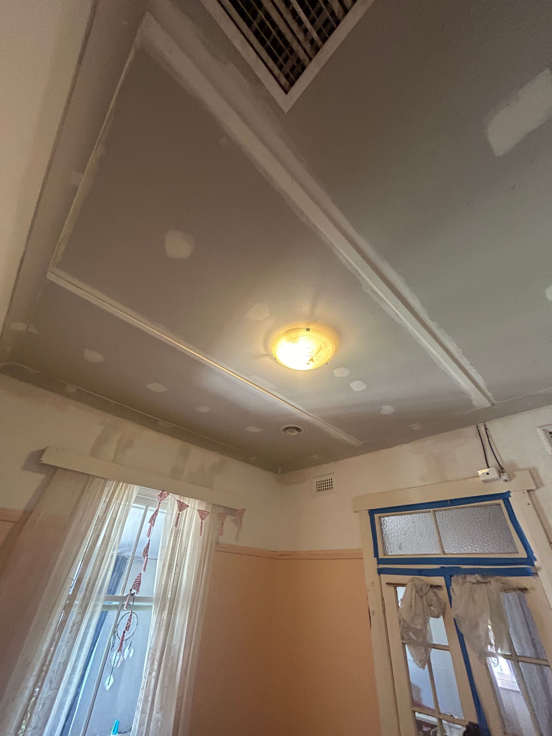 Ceiling with recessed panels and a central light fixture, along with windows and door frames.