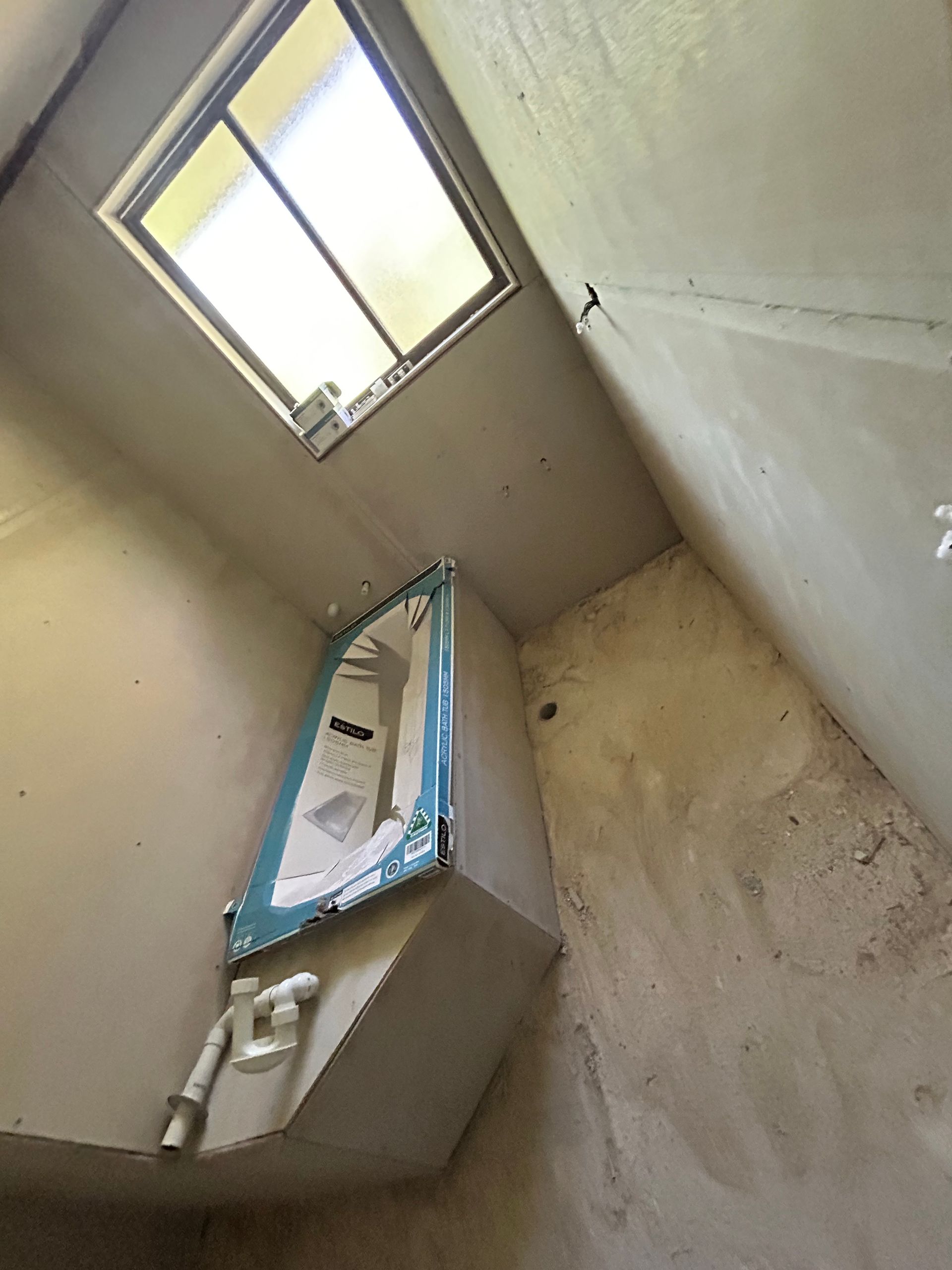 Small, unfinished bathroom with a partially installed sink and a skylight.