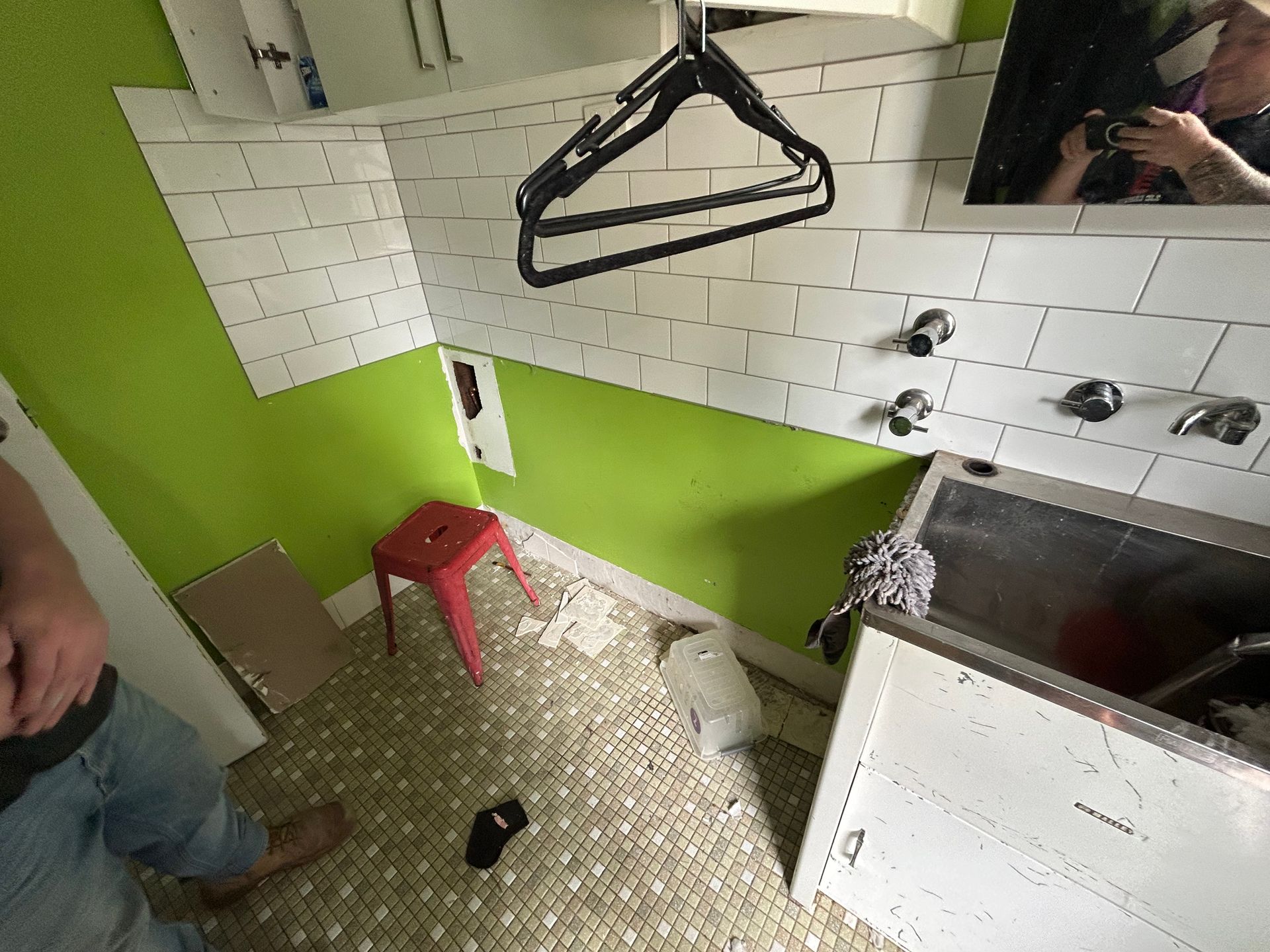 Laundry room with lime green wall and white tiles; red stool, black hanger.