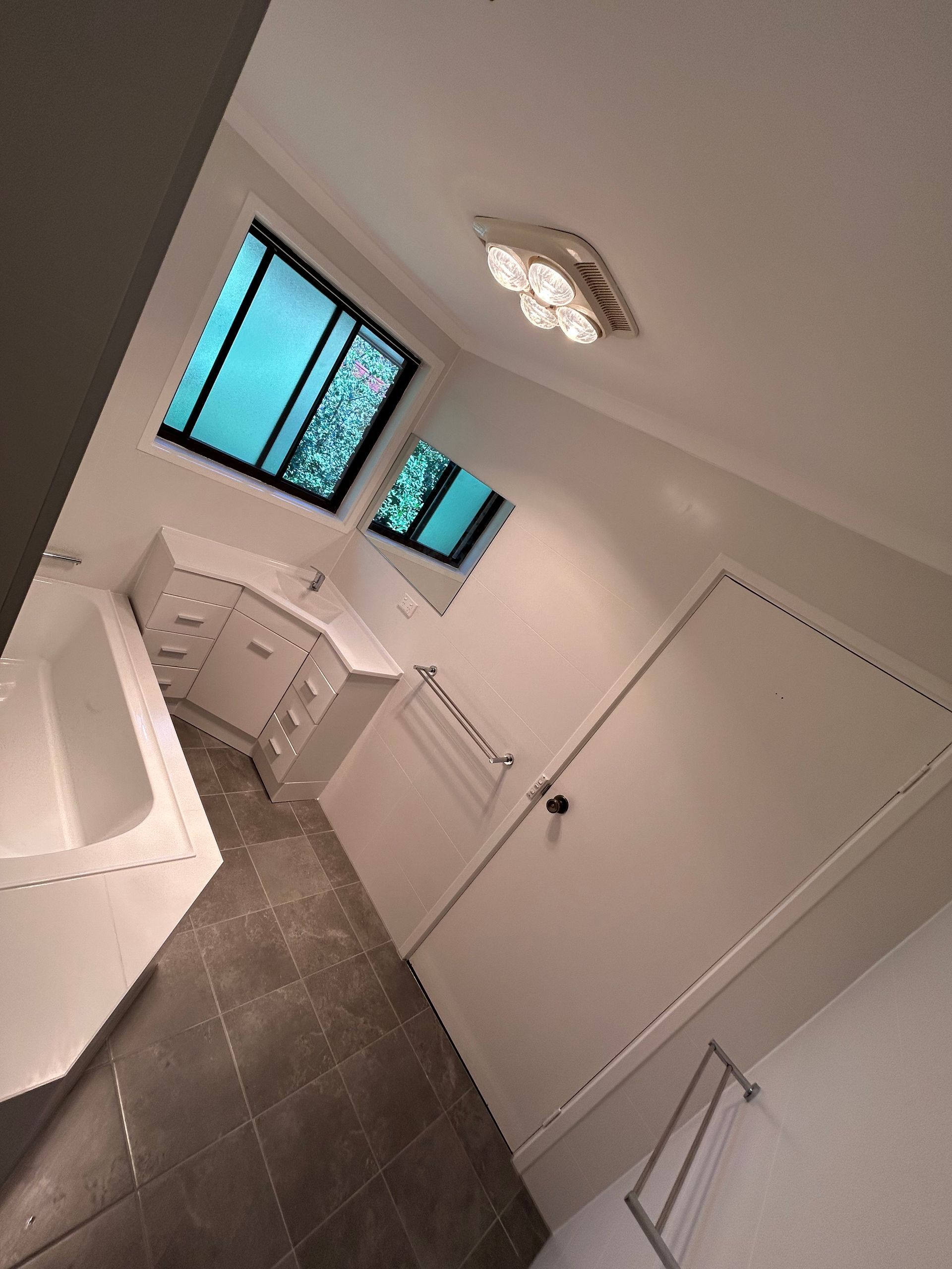 Bathroom with white cabinets, dark tile floor, and a window with a blue view.