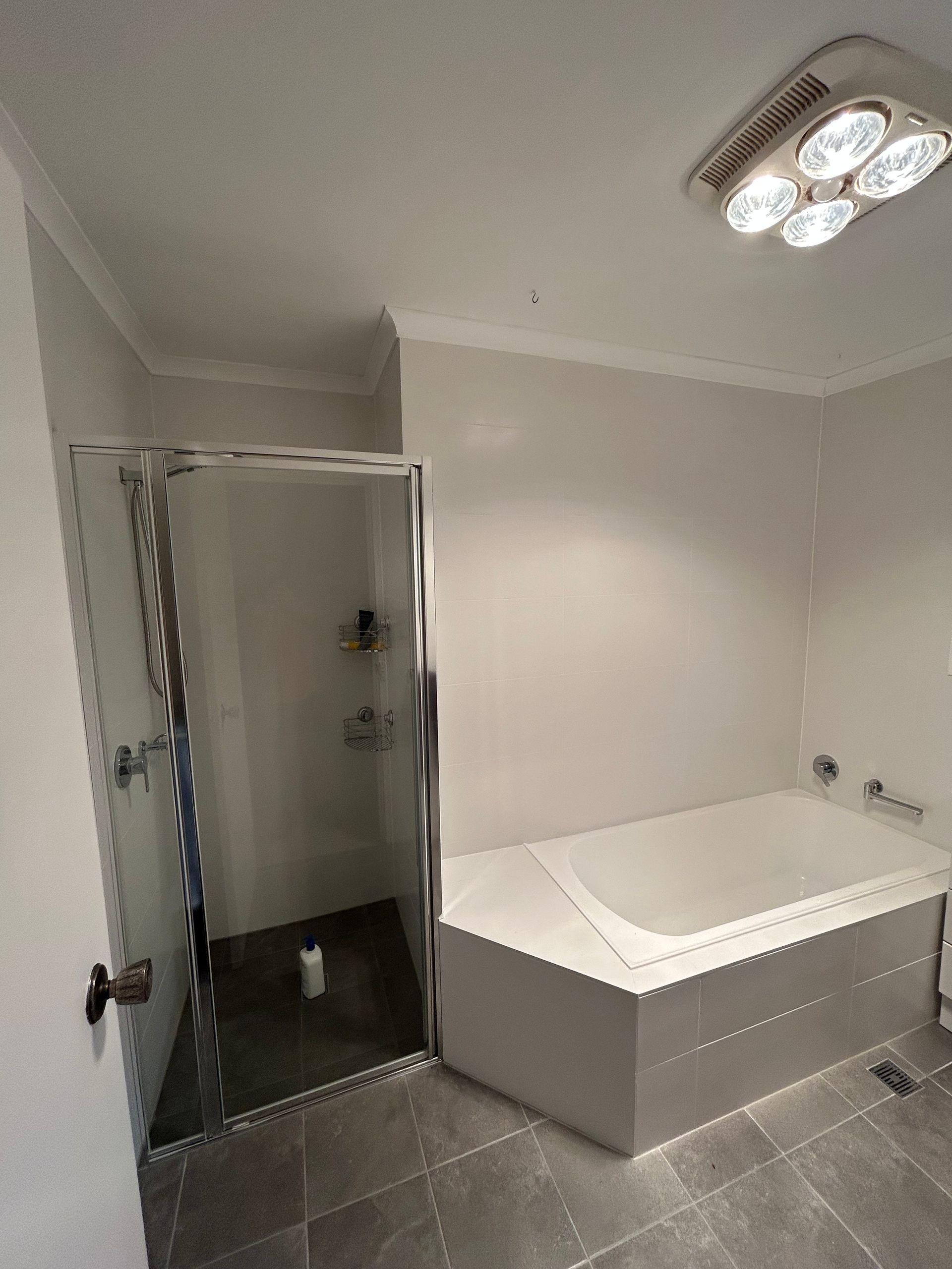 Bathroom with shower stall, built-in tub, and gray tile floor. White walls, chrome fixtures.