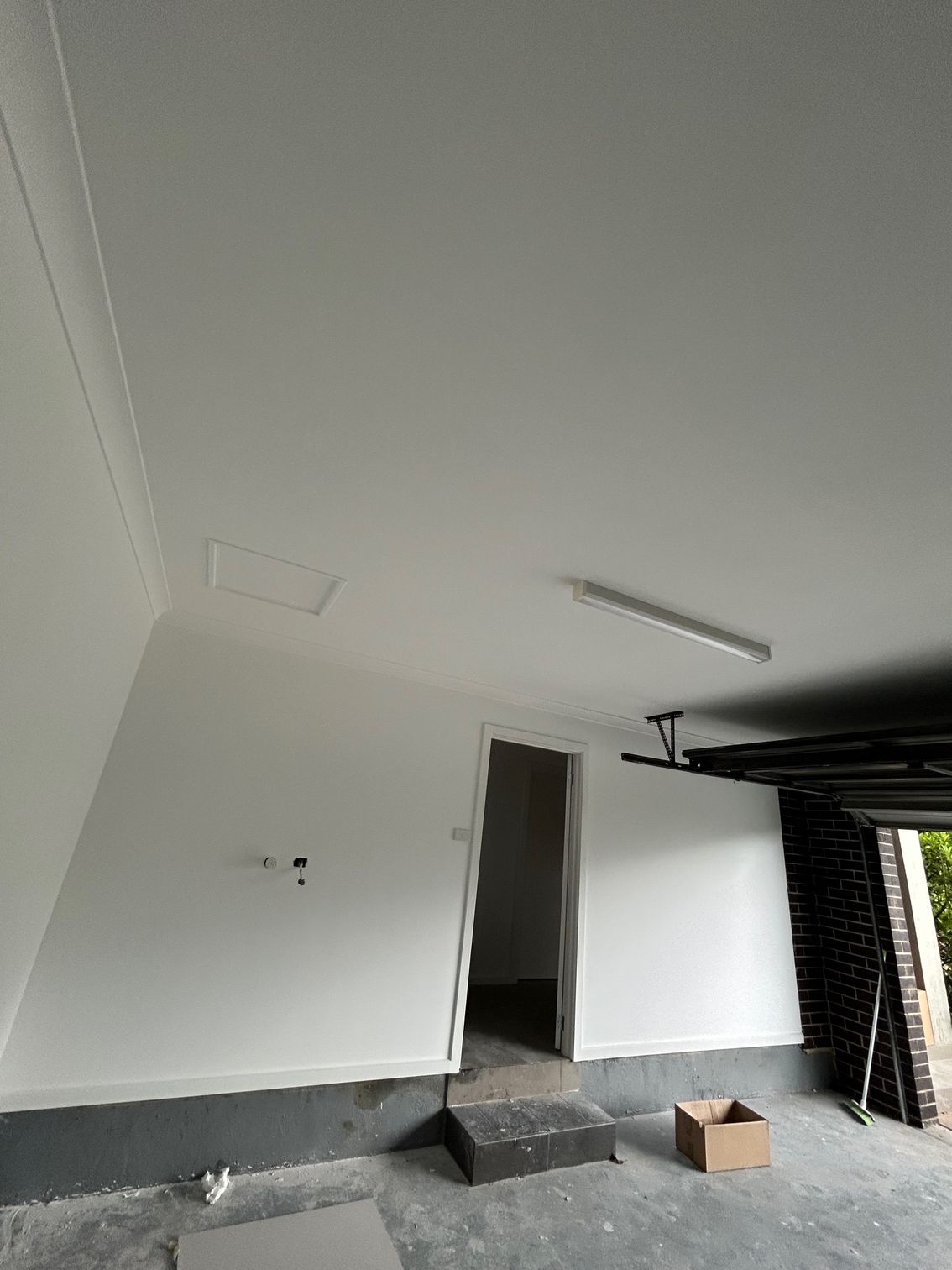 White painted garage interior with open door, light fixture, and cardboard box.