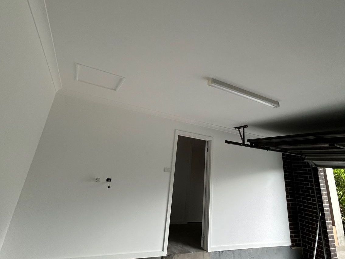 White painted room with a door, light fixture, and ceiling access panel.