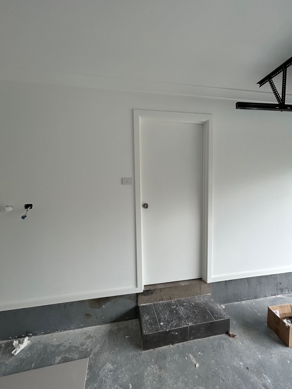 White door in a garage with a step, painted walls, and equipment.