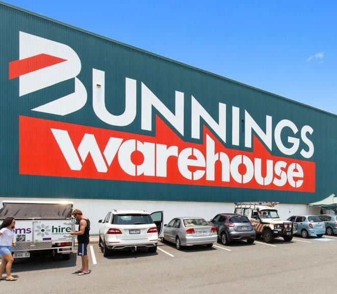 Bunnings Warehouse exterior with parked cars and people. Large signage, blue and red colors.