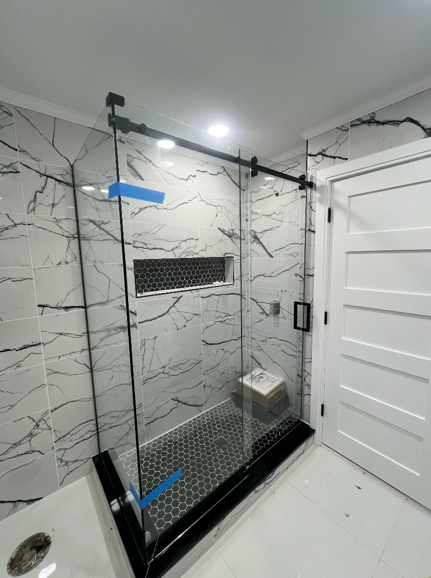 A bathroom with a sliding glass shower door and marble walls.