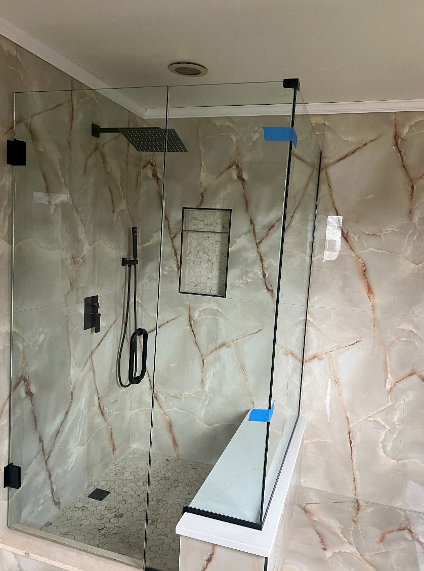 A bathroom with a walk in shower with a glass door.