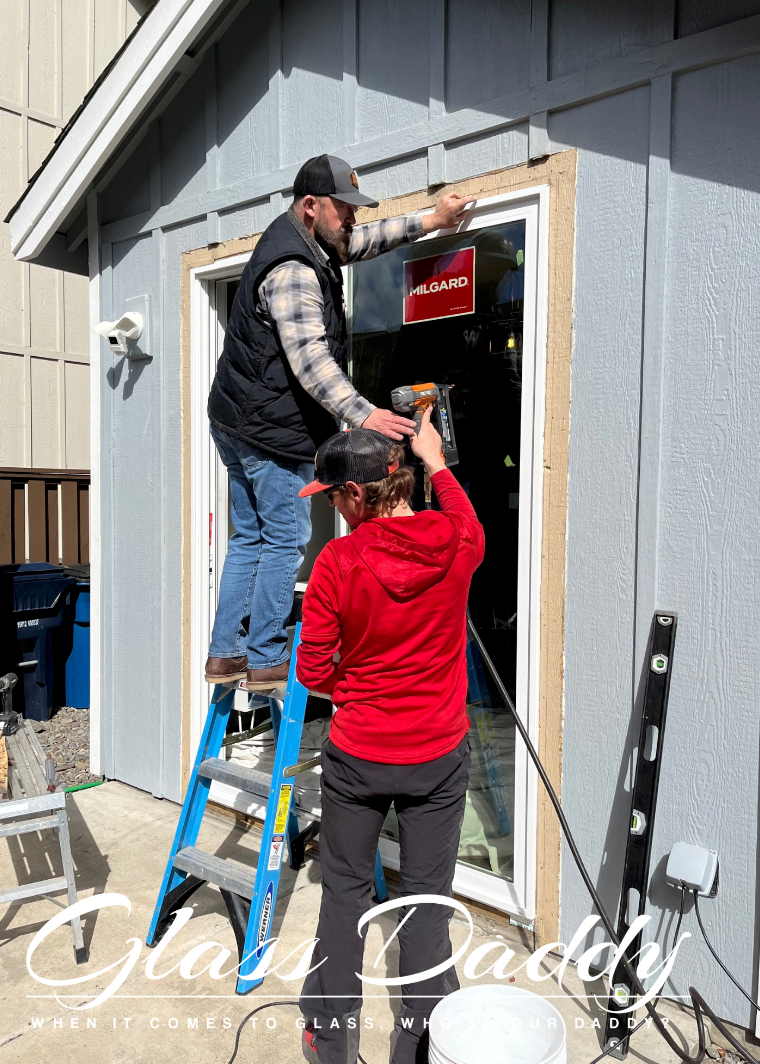 A man and a woman are working on a garage door.