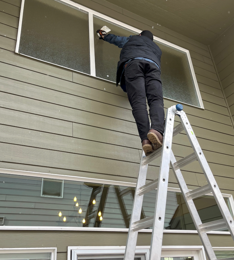 A man is standing on a ladder cleaning a window
