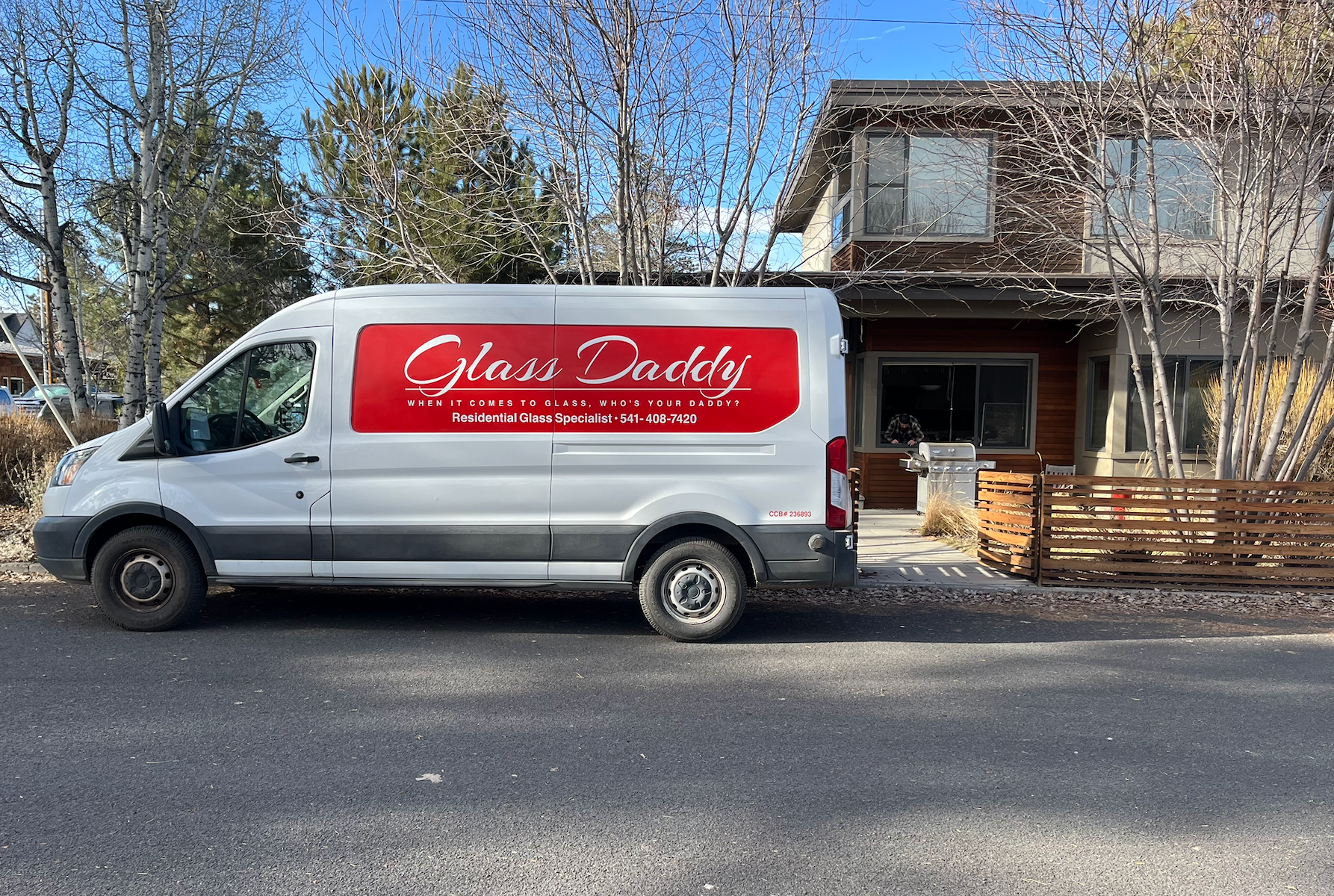 White Glass Daddy van parked in front of a modern home; red logo on the side.