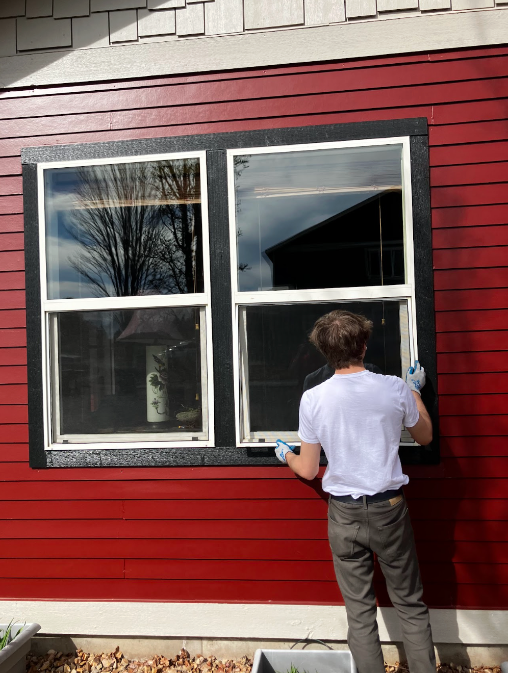 Person installing Full Window replacement in bend on red house
