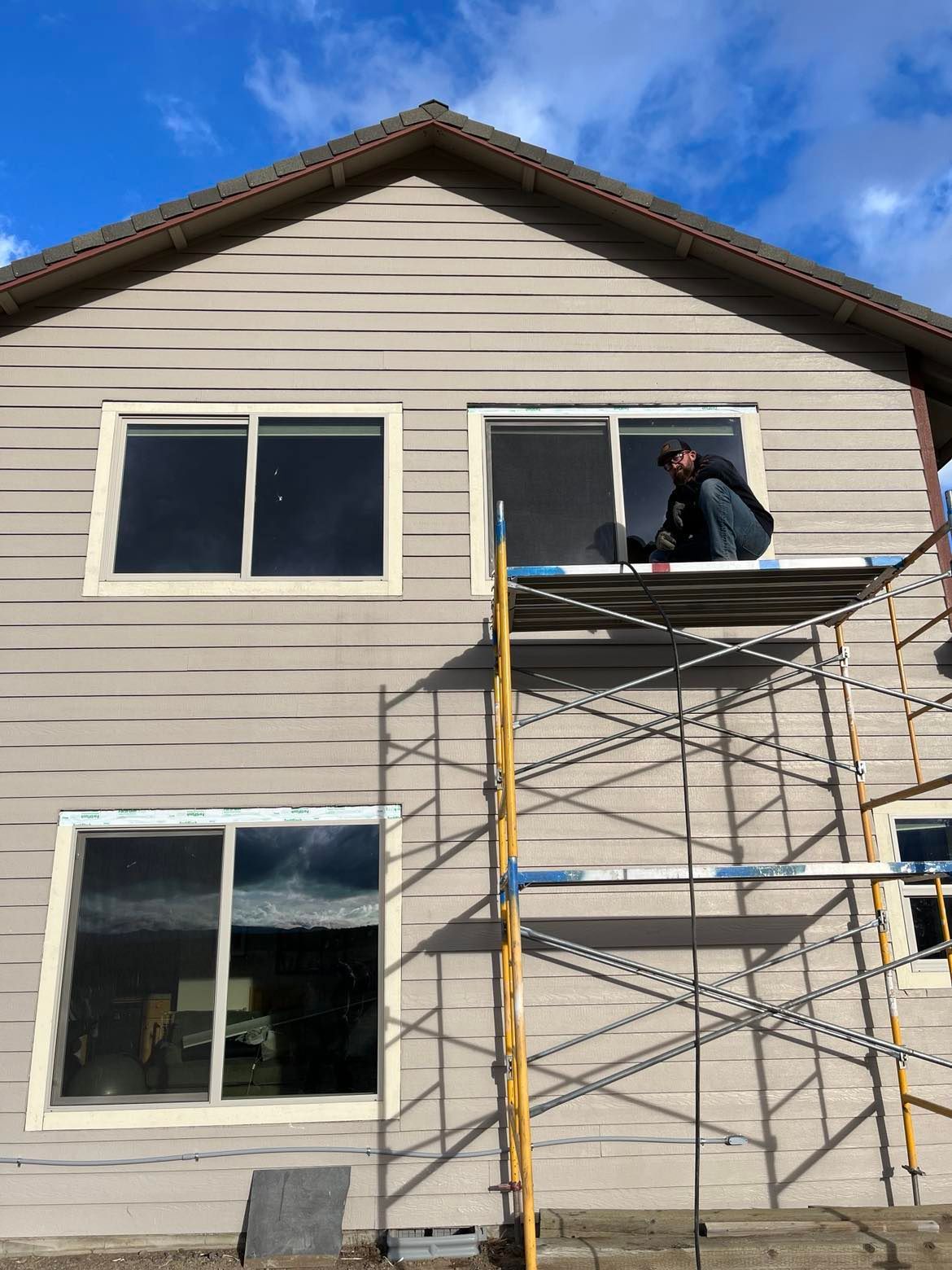 A man is standing on a scaffolding in front of a house.