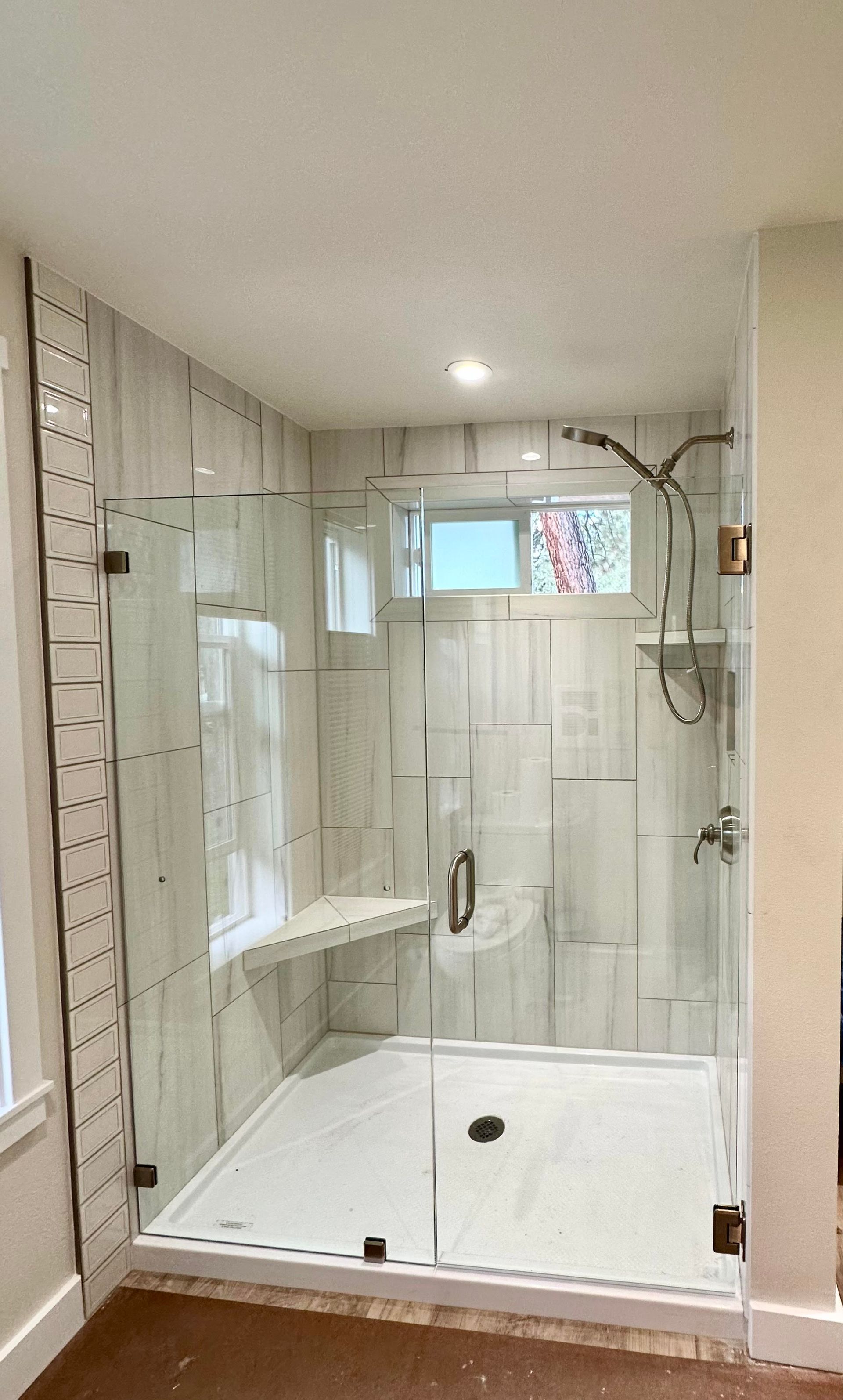 A bathroom with a walk in shower and a window.