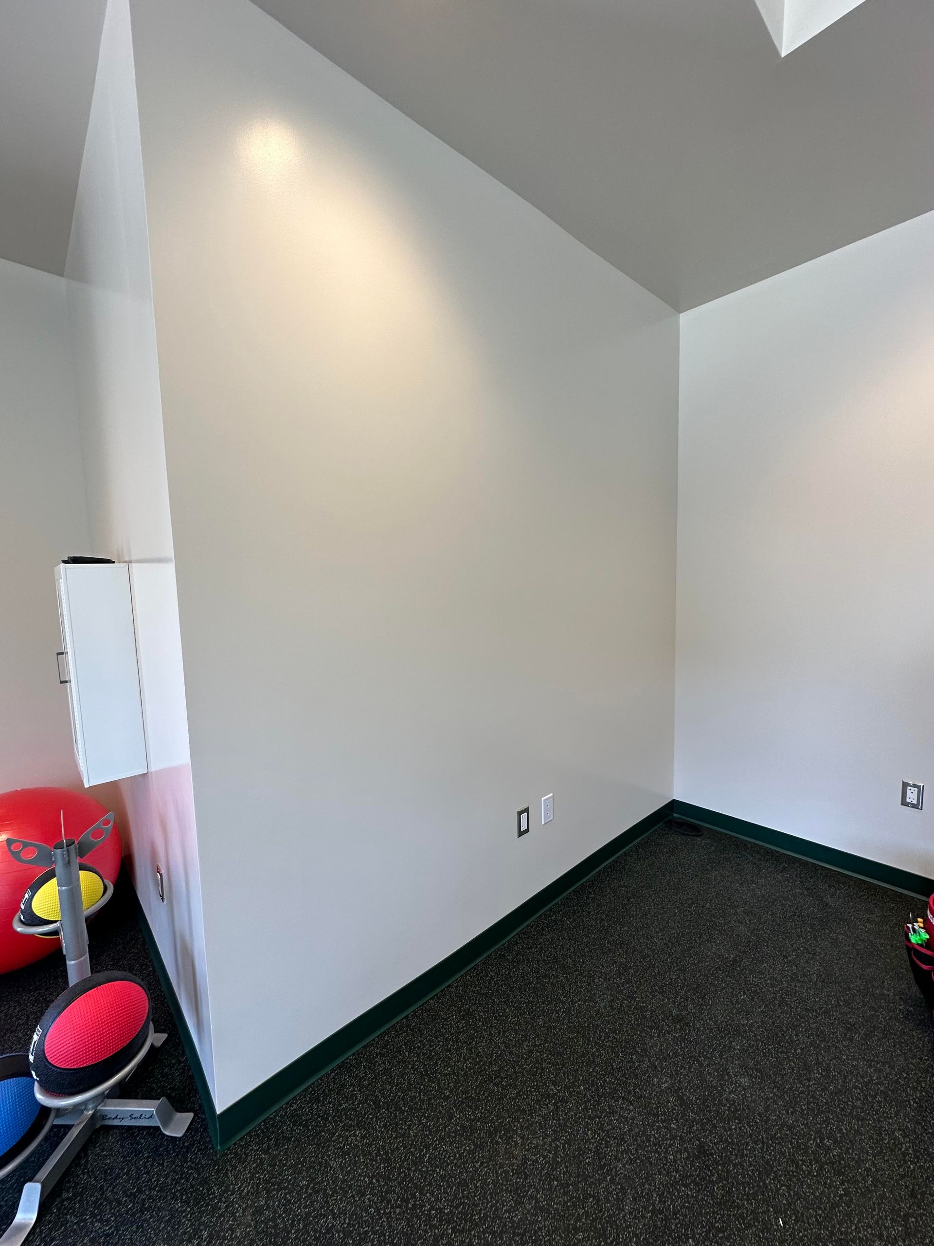 An empty room with white walls and a black floor.