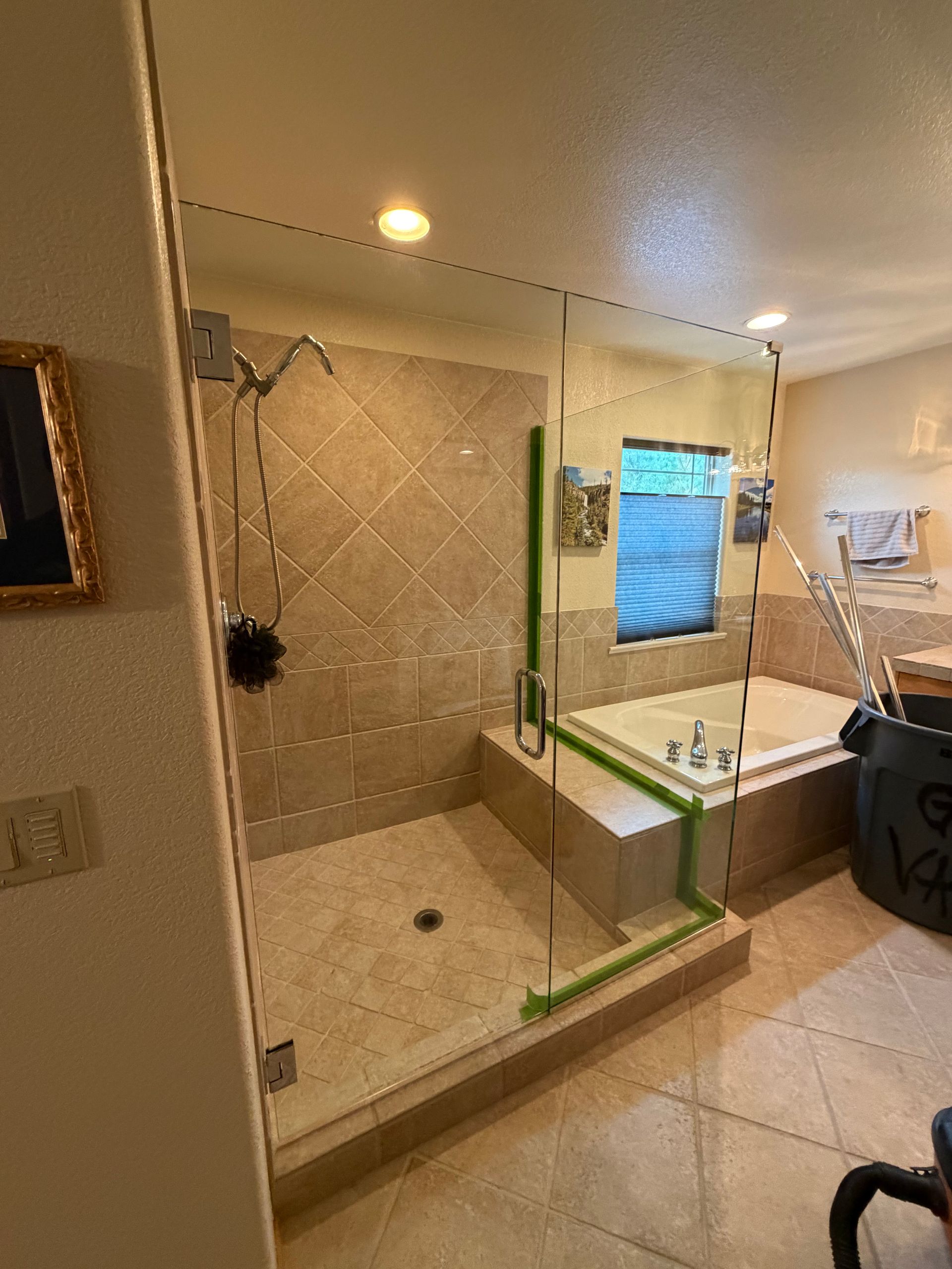 Bathroom with beige tile, Frameless shower Glass, and soaking tub near a small window.